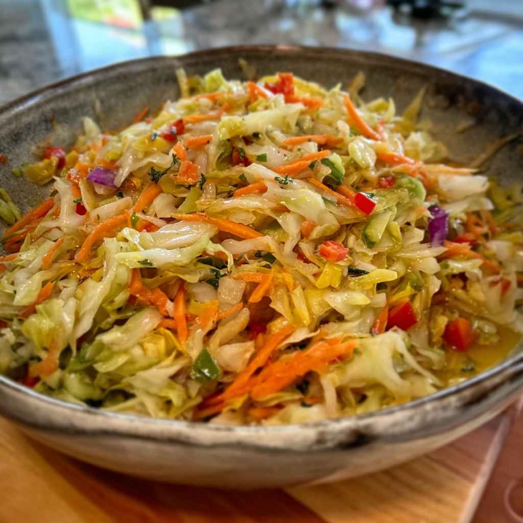 Jamaican Cabbage Coleslaw Recipe - delicate fresh leaves tossed with vibrant seasonal toppings with fresh cracked pepper and lemon wedges