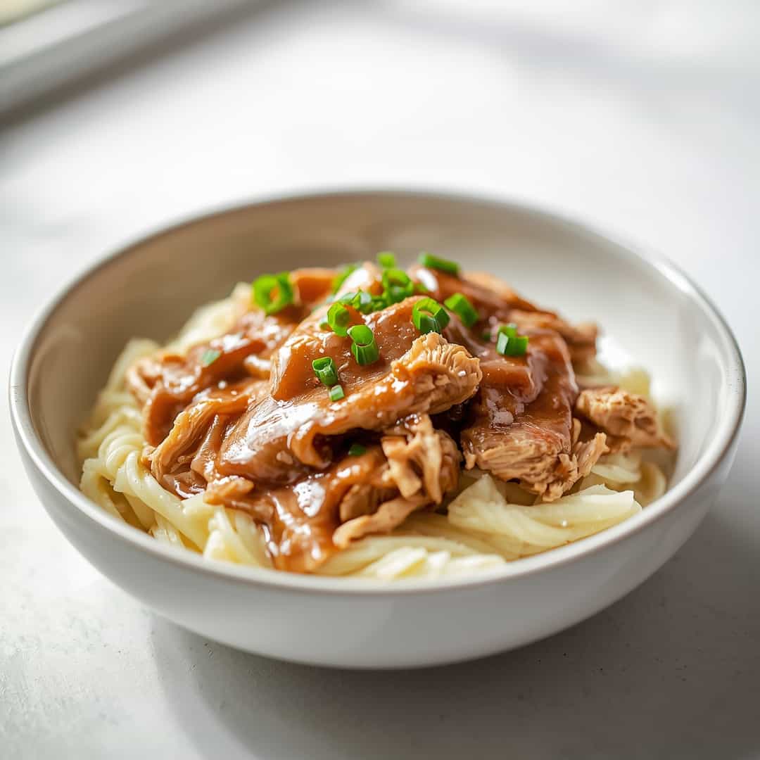 Shredded Chicken and Gravy - succulent simmered chicken smothered in rich pan sauce with fresh rosemary sprigs and pan drippings